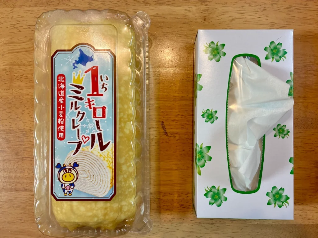 ロピア「1キロールミルクレープ」と箱ティッシュを並べた写真。ほぼ同じ大きさということがわかる。