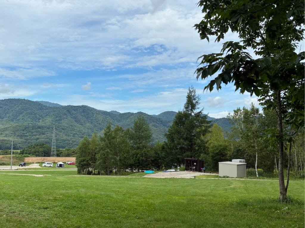 MOUNT NIKIキャンプ場レビュー記事画像｜丘の上カーサイト「O8」から水場・トイレを眺めたところ。青いものがプール。