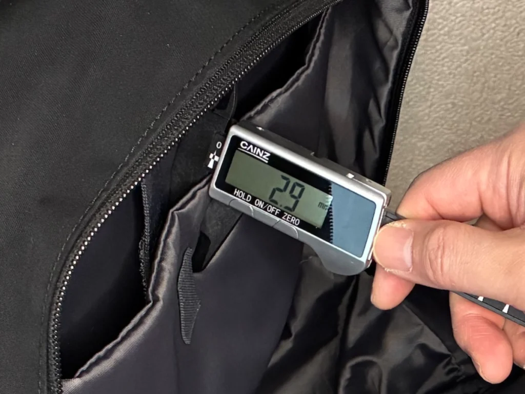 ユニクロのファンクショナルバックパックのPCポケット仕切り（2.9mm）をノギスで測定している様子