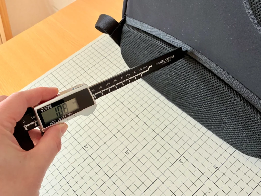 ユニクロのファンクショナルバックパックの背面パッド（約10mm厚）をデジタルノギスで測定している様子