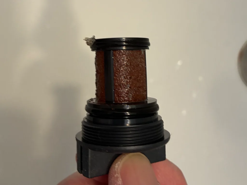 給水ストレーナーのメッシュにサビ汚れがびっしり詰まった状態（清掃前の真横からのアングル）