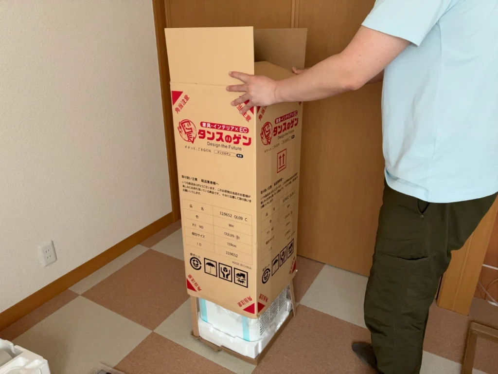 PPバンドを切ったあと、タンスのゲンのスポットクーラーの梱包箱を上に持ち上げて開封している様子