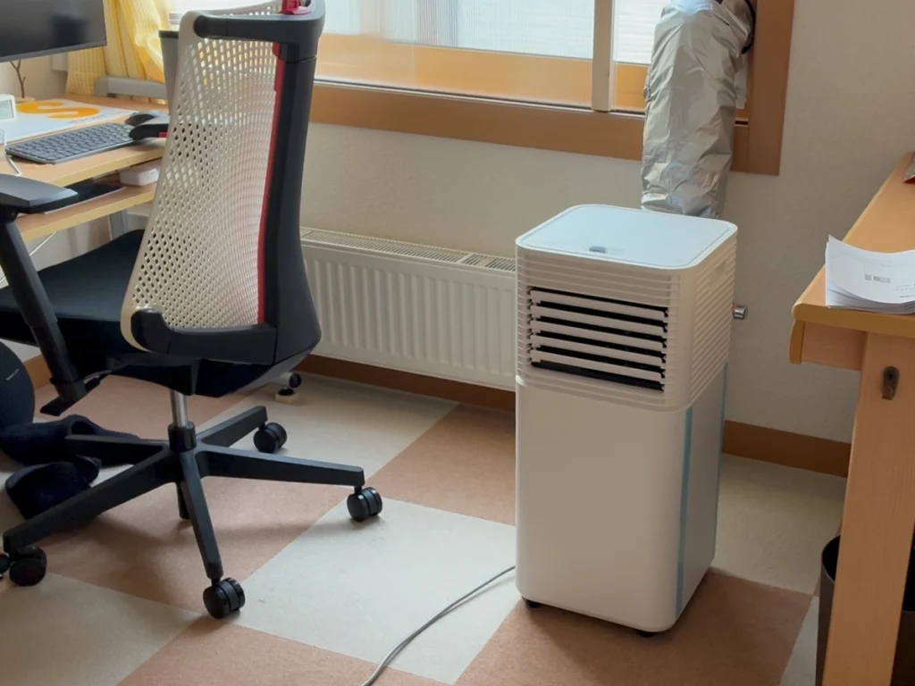 6畳の作業部屋に設置したタンスのゲンのスポットクーラーと窓へ伸ばした排熱ダクト