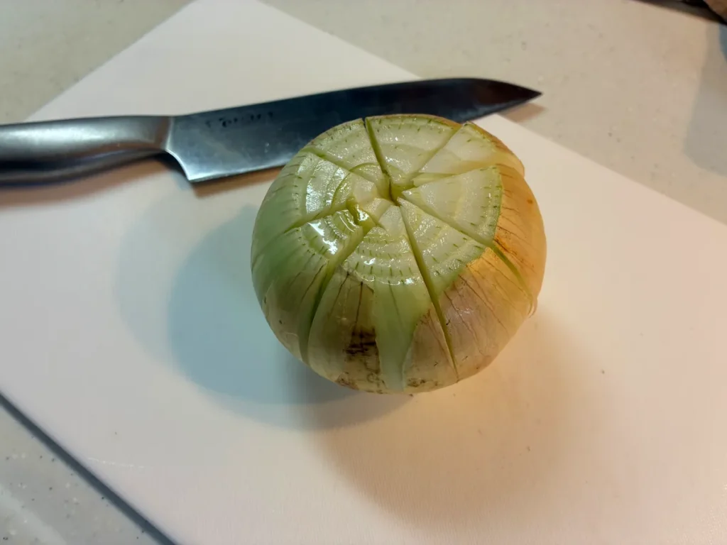 上から8等分の切り込みを入れた丸ごとの玉ねぎ