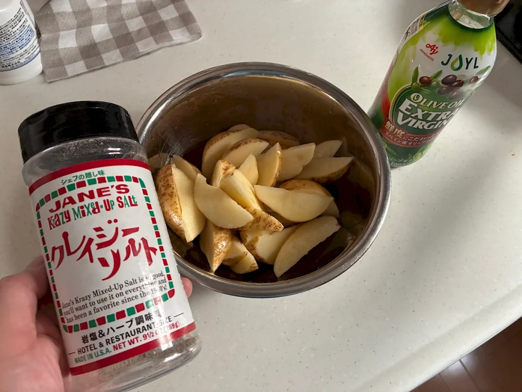 男爵じゃがいもにオリーブオイルとクレイジーソルトで味付けする様子