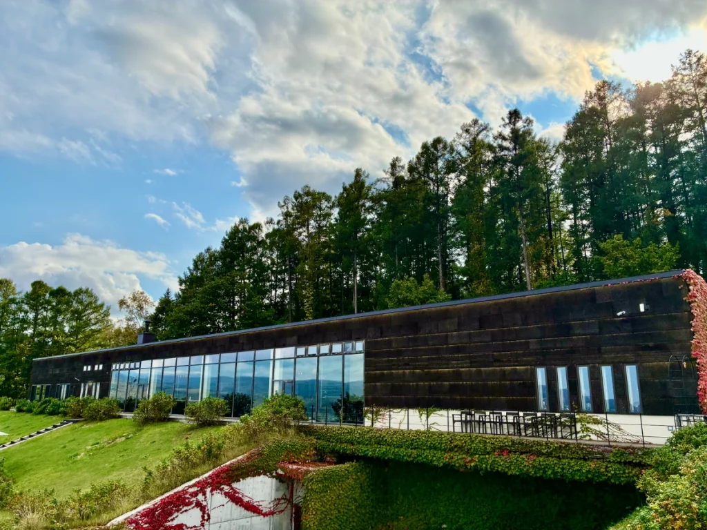 NIKI Hills Wineryの大きなガラス窓が並ぶ建物外観と屋外テラス