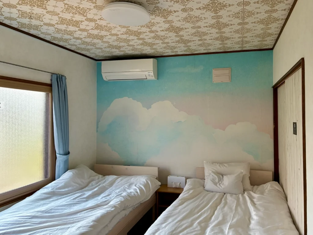 Yoichi Niki Retreatの1階寝室に並ぶ2台のシングルベッドとエアコン